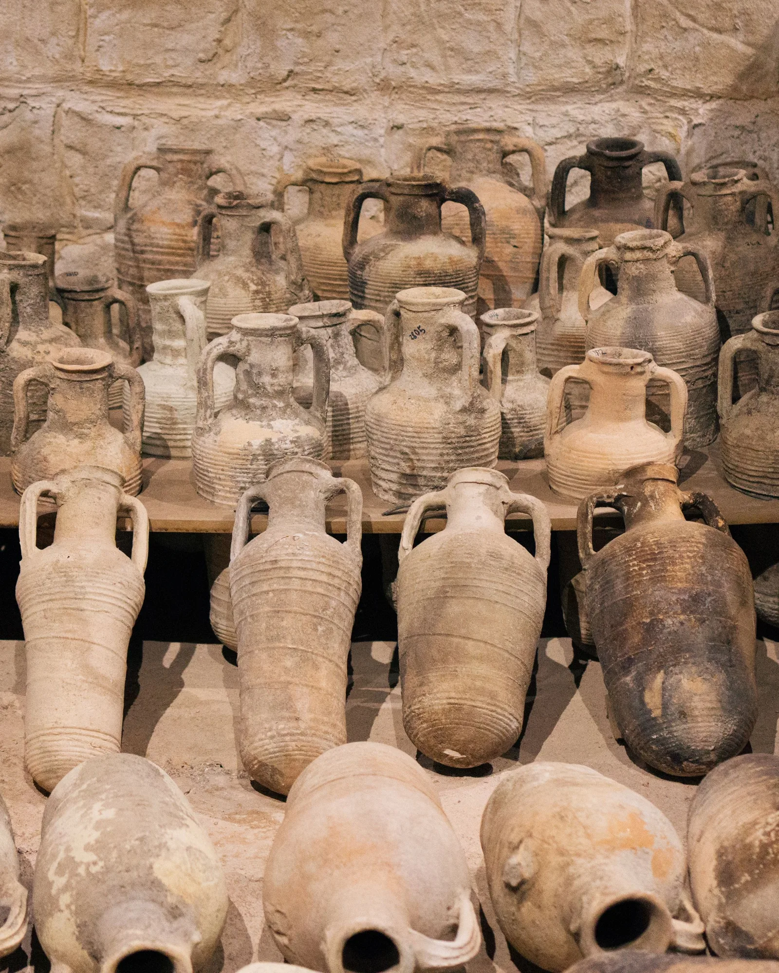 Amphores antiques en terre cuite alignées dans une salle de musée d’archéologie